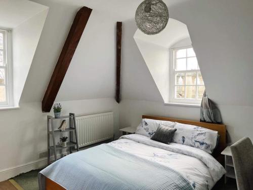 a bedroom with a bed and two windows at 4 bed loft apartment overlooking historic town in Trowbridge