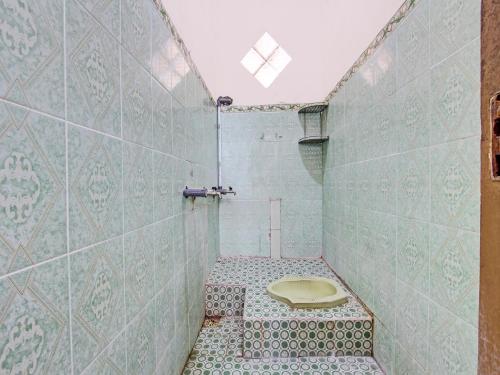 a bathroom with a toilet in a tiled wall at SPOT ON 92319 White House Syariah in Yogyakarta