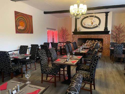 a dining room with tables and chairs and a fireplace at Scole Inn Hotel in Diss