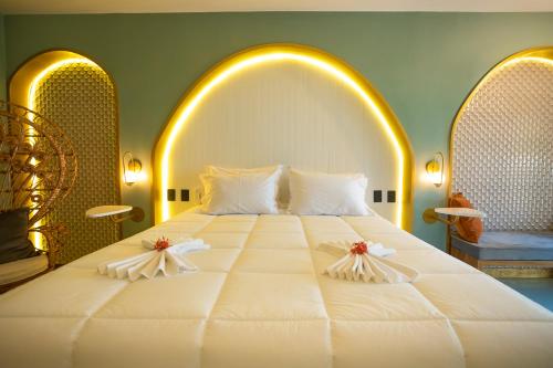 a bedroom with a large white bed with two pillows at Exótica Boutique Hotel in Pipa