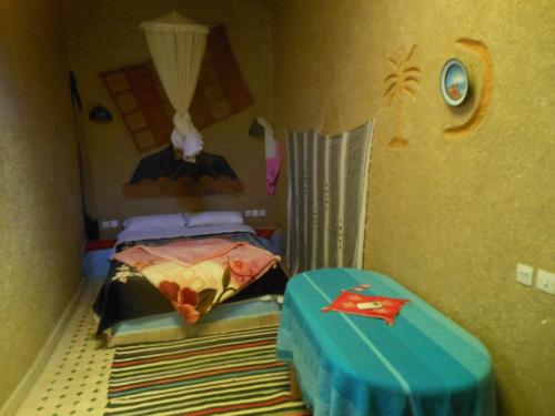 a small room with a bed and a table at Riad Aicha & Camel Trekking in Merzouga