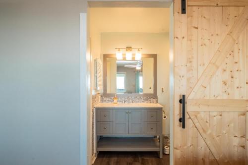 a bathroom with a sink and a mirror and a door at Castaway in Caswell Beach