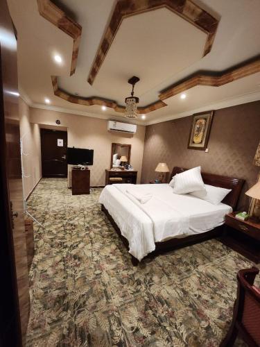 a bedroom with a large white bed and a television at فندق شموخ السعد in Mecca