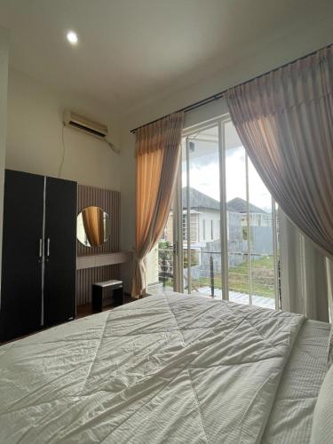 ein Schlafzimmer mit einem großen Bett und einem großen Fenster in der Unterkunft Apple eight 2BR Villa in Batu