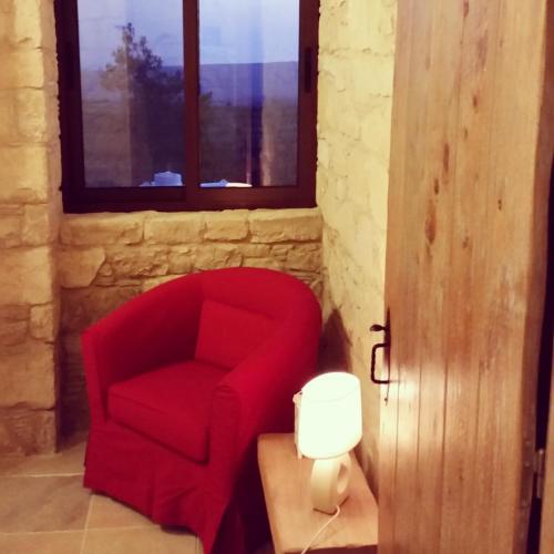 a red chair in a room with a window at Lofou Traditional Stone House in Lofou