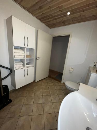 La salle de bains est pourvue d'un lavabo blanc et de toilettes. dans l'établissement Hyggelig lejlighed i Rinkenæs, à Gråsten