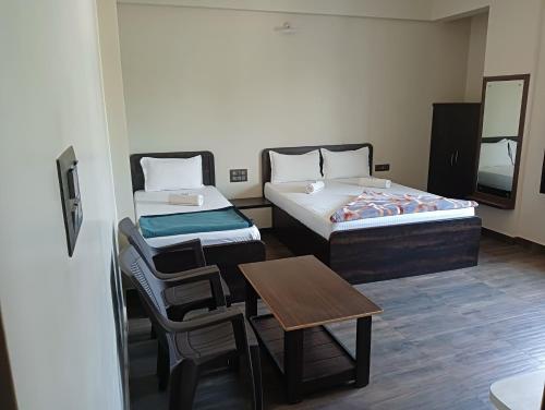 Zimmer mit 2 Betten, einem Tisch und einem Stuhl in der Unterkunft HONNASIRI RESIDENCY in Shimoga