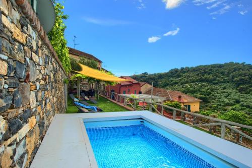 basen na boku budynku z kamienną ścianą w obiekcie casa con piscina, giardino e area giochi per bambini w mieście Diano San Pietro