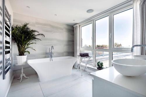 a bathroom with a large white tub and a large window at Luxury Panoramic 3 bed with private terrace in London