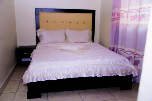 - une chambre avec un grand lit et une couette blanche dans l'établissement PARADOR MOTEL KIGALI, à Kigali