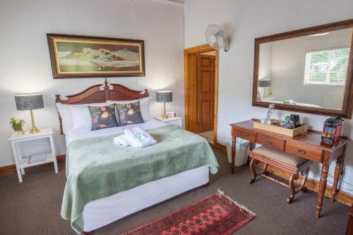 a bedroom with a bed and a mirror and a table at The Vineyard Country House in Montagu