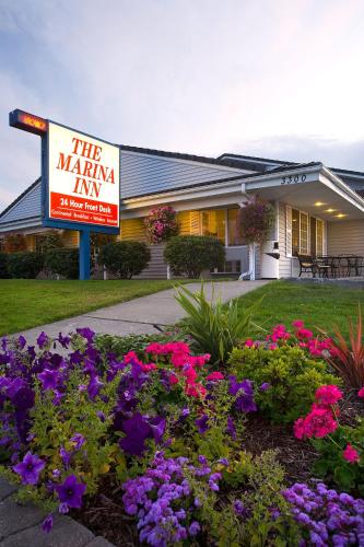 a sign in front of a building with flowers at The Marina Inn in Anacortes