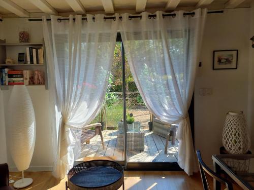 FuveauにあるGîte Le Logis Vallatの白いカーテン付きの大きな窓が備わる客室です。