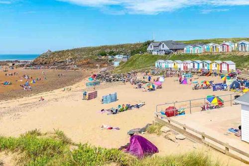 a beach with a bunch of people on the sand at First floor apartment in Stratton, Bude in Stratton