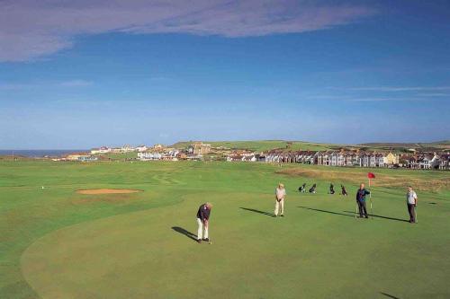 a group of people playing golf on a golf course at First floor apartment in Stratton, Bude in Stratton