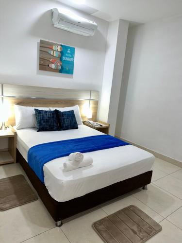 a bedroom with a large bed with blue and white sheets at Hotel Boutique Deluxe in Santa Marta