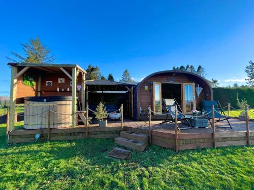 a house with a deck in the grass at FINN VILLAGE - Loch Lomond Sunset Glamping Pod - Private Ofuro HOT TUB in Drymen