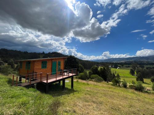 ein winziges Haus auf einem Hügel mit einer Terrasse in der Unterkunft Huitaca Glamping in Paipa