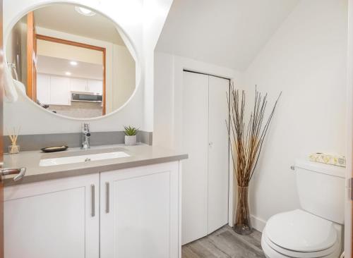 a white bathroom with a sink and a mirror at Amazing Village Location with PRIVATE Hot Tub in Whistler