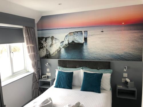 a bedroom with a bed with a painting on the wall at Swanage Haven Boutique Guest House in Swanage