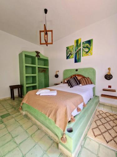 a bedroom with a large bed with a green headboard at Les Villas de Nouran 7chambres in Ghazoua