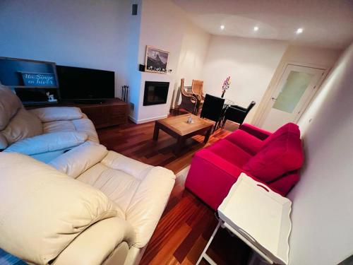 un soggiorno con divano e sedia rossa di Coqueto apartamento en Las margas golf a Sabiñánigo