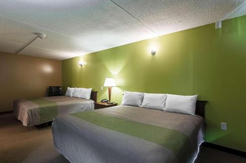 een hotelkamer met 2 bedden en een groene muur bij LoneStar Inn and Suites in Sherman