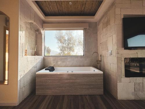 een badkamer met een bad en een raam bij Penthouse at Hotel Boutique Valle de Guadalupe in Valle de Guadalupe