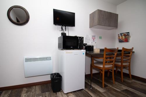 Il comprend une cuisine équipée d'un réfrigérateur et d'une table avec des chaises. dans l'établissement Motel Au Bord de l'Eau, à Rimouski