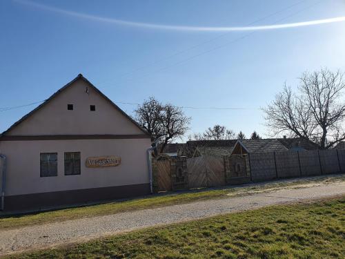 a white building with a fence next to a road at Village Story kuća za odmor Plavna in Plavna
