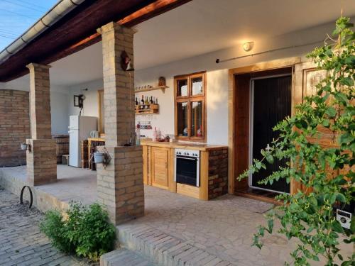 an outdoor kitchen with wooden cabinets and an open door at Village Story kuća za odmor Plavna 
