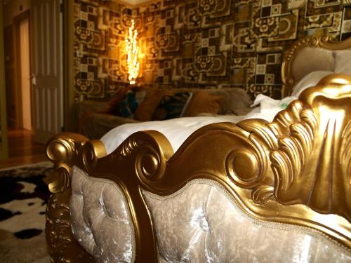 a gold bed in a room with a couch at Deluxe 4 5 Bed Hot Tub Cinema Room 15 in Saffron Walden