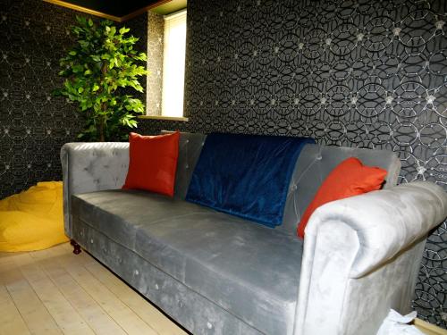 a gray couch with colorful pillows on it at Deluxe 4 5 Bed Hot Tub Cinema Room 15 in Saffron Walden