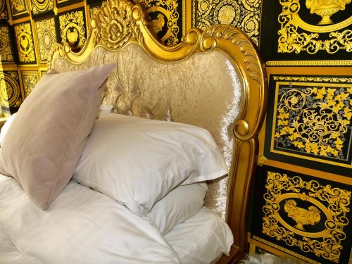 a bed with a gold head board with a pillow at Deluxe 4 5 Bed Hot Tub Cinema Room 15 in Saffron Walden