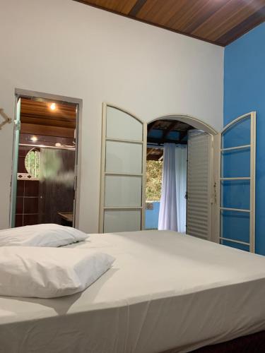 a bedroom with a large white bed and a window at Pousada camping Recanto Joanópolis in Joanópolis