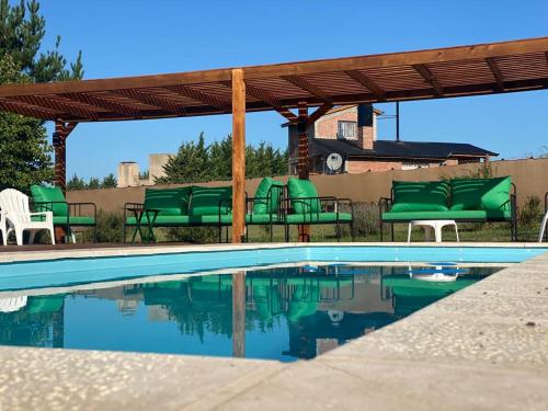 una piscina con sillas verdes y pérgola en Los Teritos en Tandil