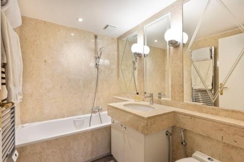 une salle de bain avec un lavabo, une baignoire et un miroir dans l'établissement croisette3bedroomterrasse, à Cannes