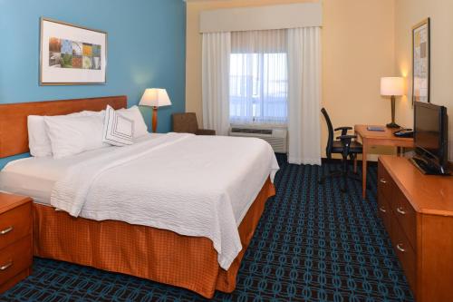 Habitación de hotel con cama, escritorio y TV. en Fairfield Inn & Suites Bloomington, en Bloomington