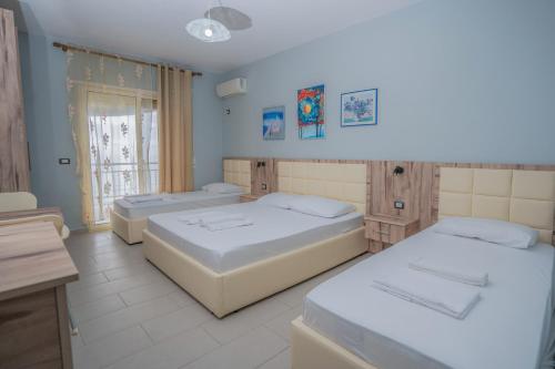 a bedroom with three beds and a window at Hotel Klebrido in Durrës