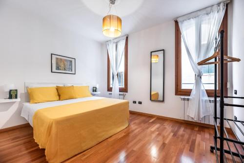 una camera da letto con letto, lenzuola gialle e pavimenti in legno di The Most Central In Venice [ San Marco Rialto ] a Venezia