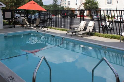 Annapolis Junction的住宿－TownePlace Suites by Marriott Fort Meade National Business Park，一个带椅子和遮阳伞的大型游泳池