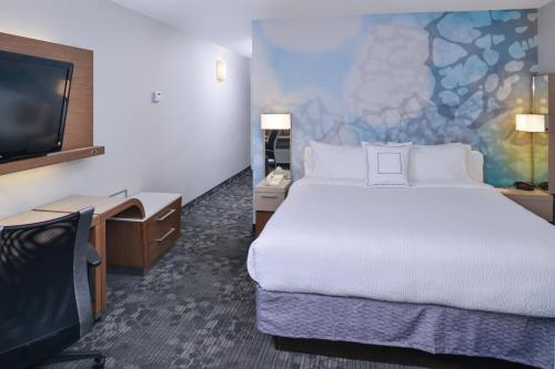 a hotel room with a bed and a flat screen tv at Courtyard Atlanta Suwanee in Suwanee