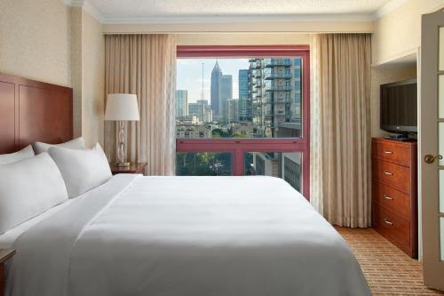 um quarto com uma grande cama branca e uma grande janela em Atlanta Marriott Suites Midtown em Atlanta