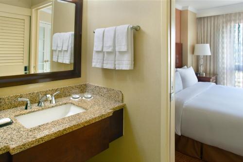 Atlanta Marriott Suites Midtown في أتلانتا: حمام مع حوض وسرير ومرآة