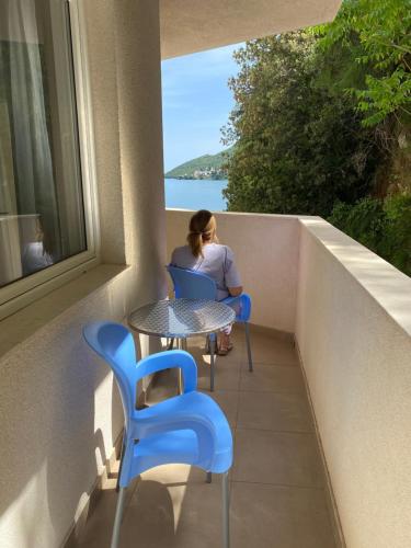 a woman sitting on a balcony with a table and chairs at Hotel Vienna in Herceg-Novi