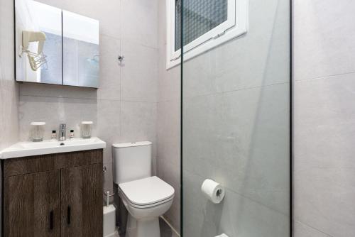 a bathroom with a toilet and a sink and a mirror at Oasis Hotel in Perama
