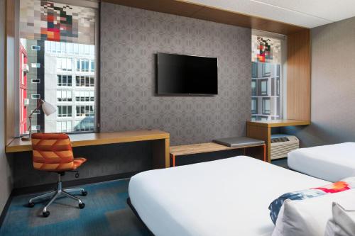 Habitación de hotel con cama, escritorio y TV. en Aloft Minneapolis, en Minneapolis