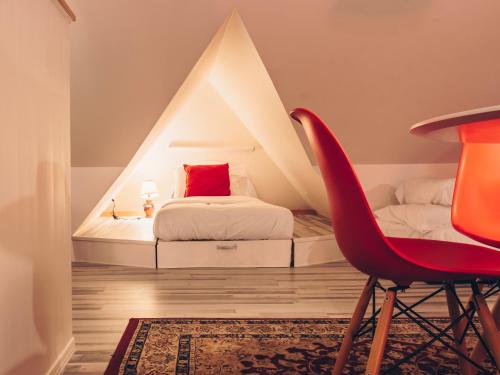 a bedroom with a bed and a red chair at Auberge aux Deux Lions in Quebec City
