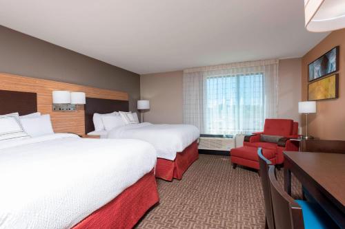 Cette chambre d'hôtel comprend deux lits et un fauteuil rouge. dans l'établissement TownePlace Suites by Marriott Ontario-Mansfield, à Mansfield
