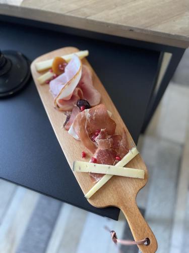 Una tabla de cortar de madera con carne y otros alimentos encima. en Château de Neyran chambre d'hôtes & Spa, en Soulac-sur-Mer